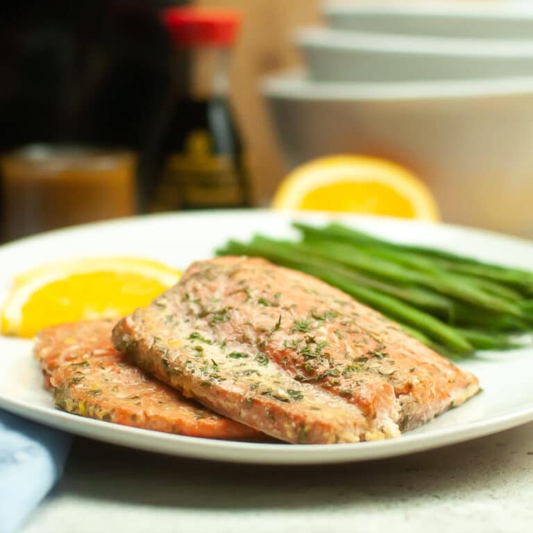 Fresh air fryer salmon fillet with an orange sauce on a white dinner plate.