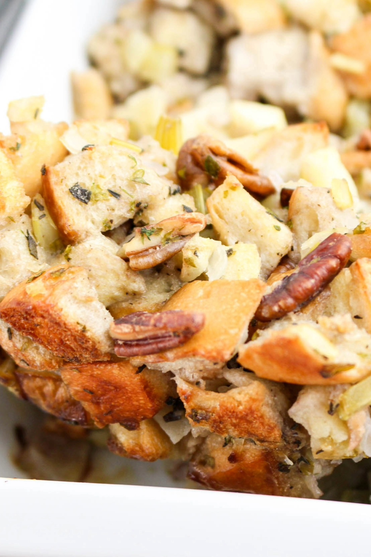 Close view of a spoonful of stuffing with pecans and herbs ready to eat.