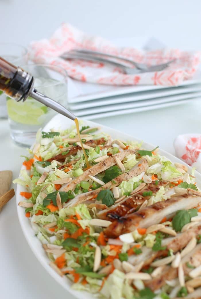 Pouring the salad dressing on our Grilled Ginger Sesame Chicken Salad.