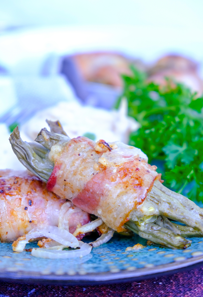 Fresh green beans wrapped in bacon on a teal plate.