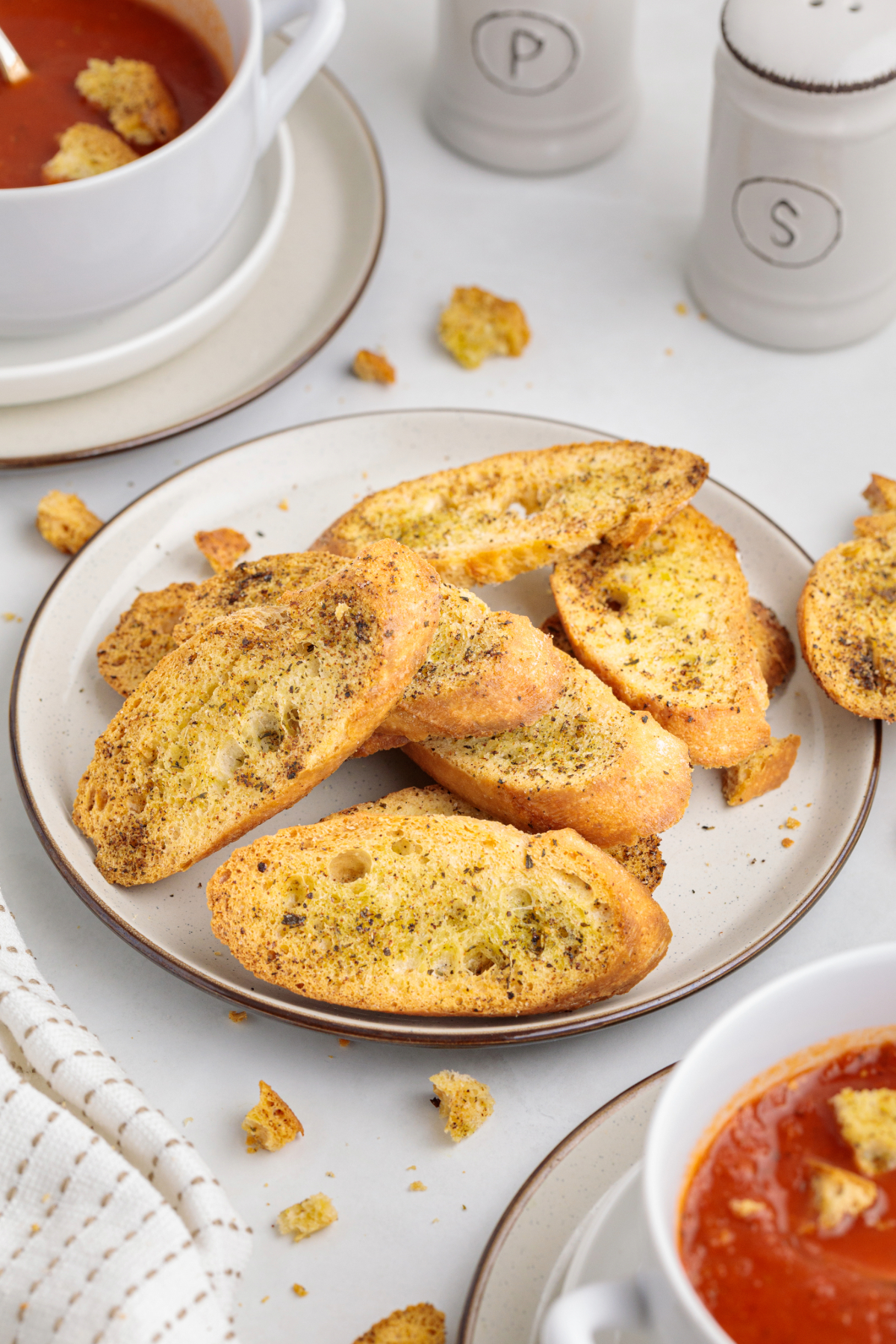 Toasted crostini on a serving plate with soup on the side.