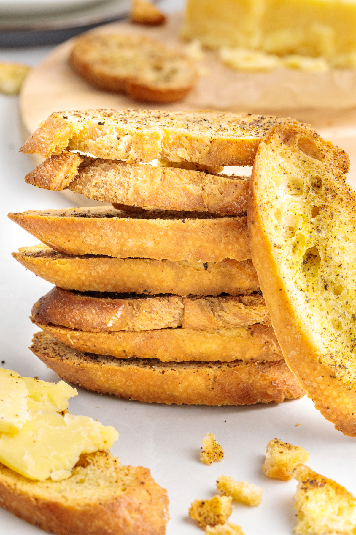 A stack of toasted crostini with a block of cheese on the side.