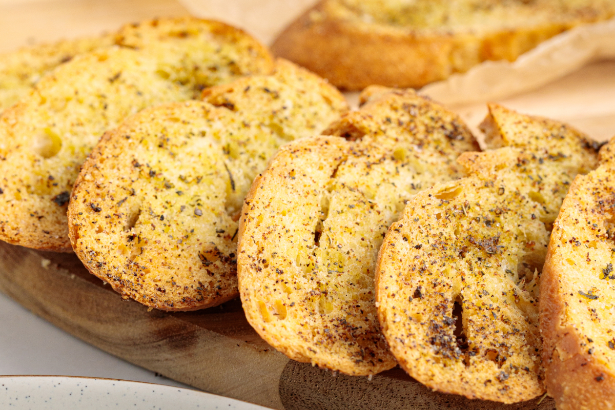 A stack of homemade crackers on a tan cutting board.