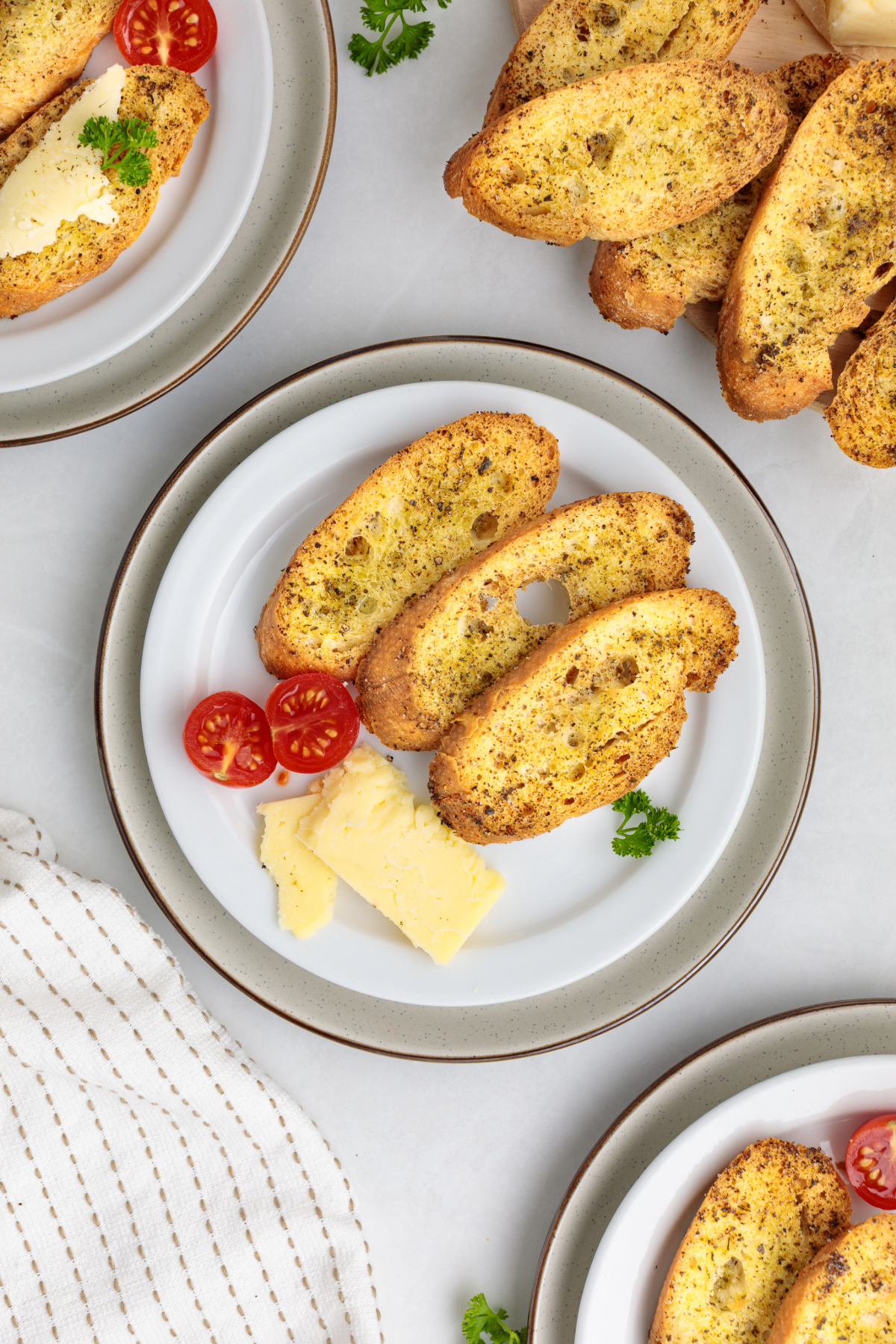 Overhead view of baguette crackers on appetizer plates with cheese and vegetables.