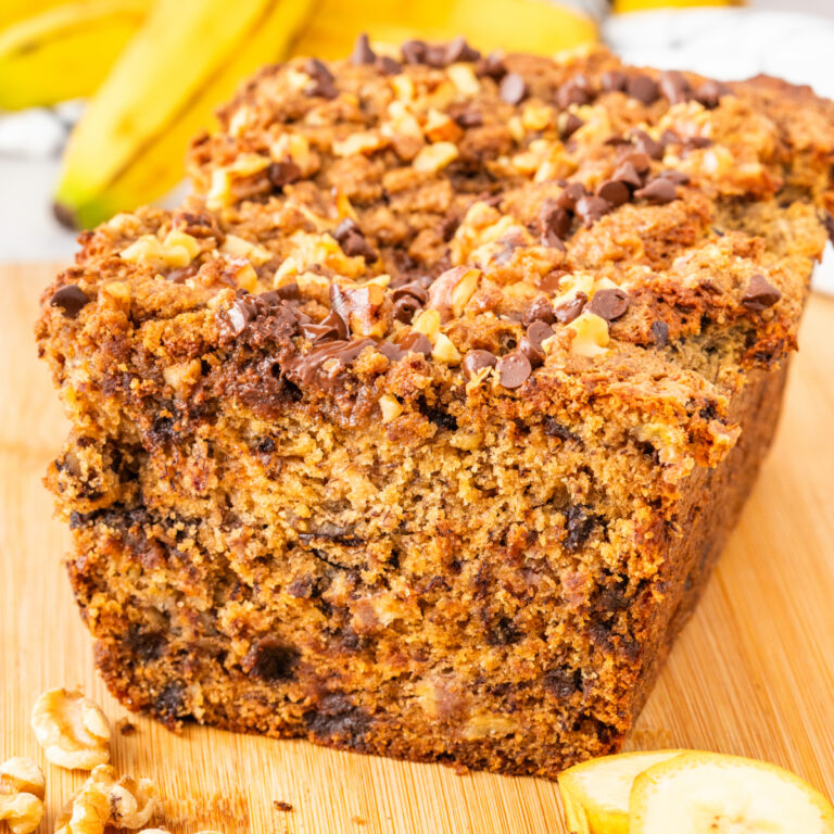 Banana bread with streusel topping on a tan cutting board.