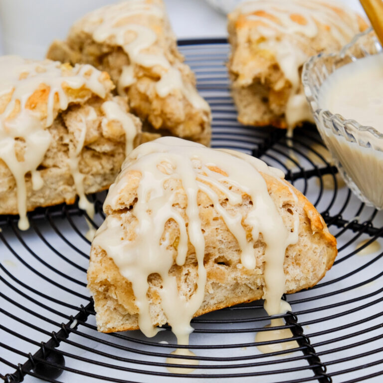 Maple glaze drizzled over banana scones on a cooling rack.