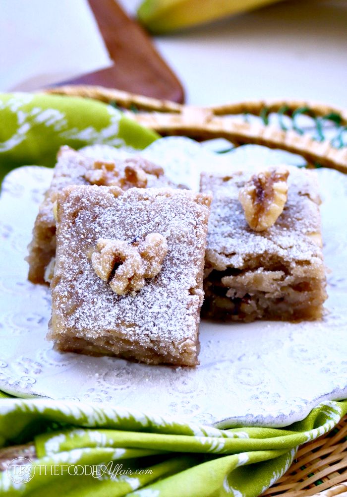 A white place of banana snack bars with a walnut on top of each piece