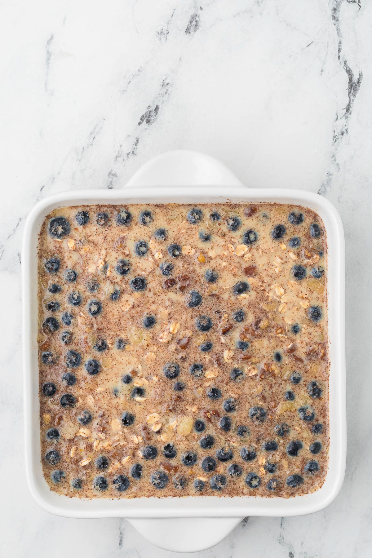 Unbaked blueberry oatmeal dish in a white baking dish.