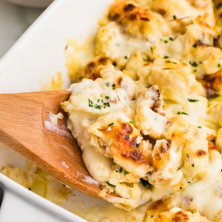 A wooden spoon of cauliflower baked with a cheese sauce.