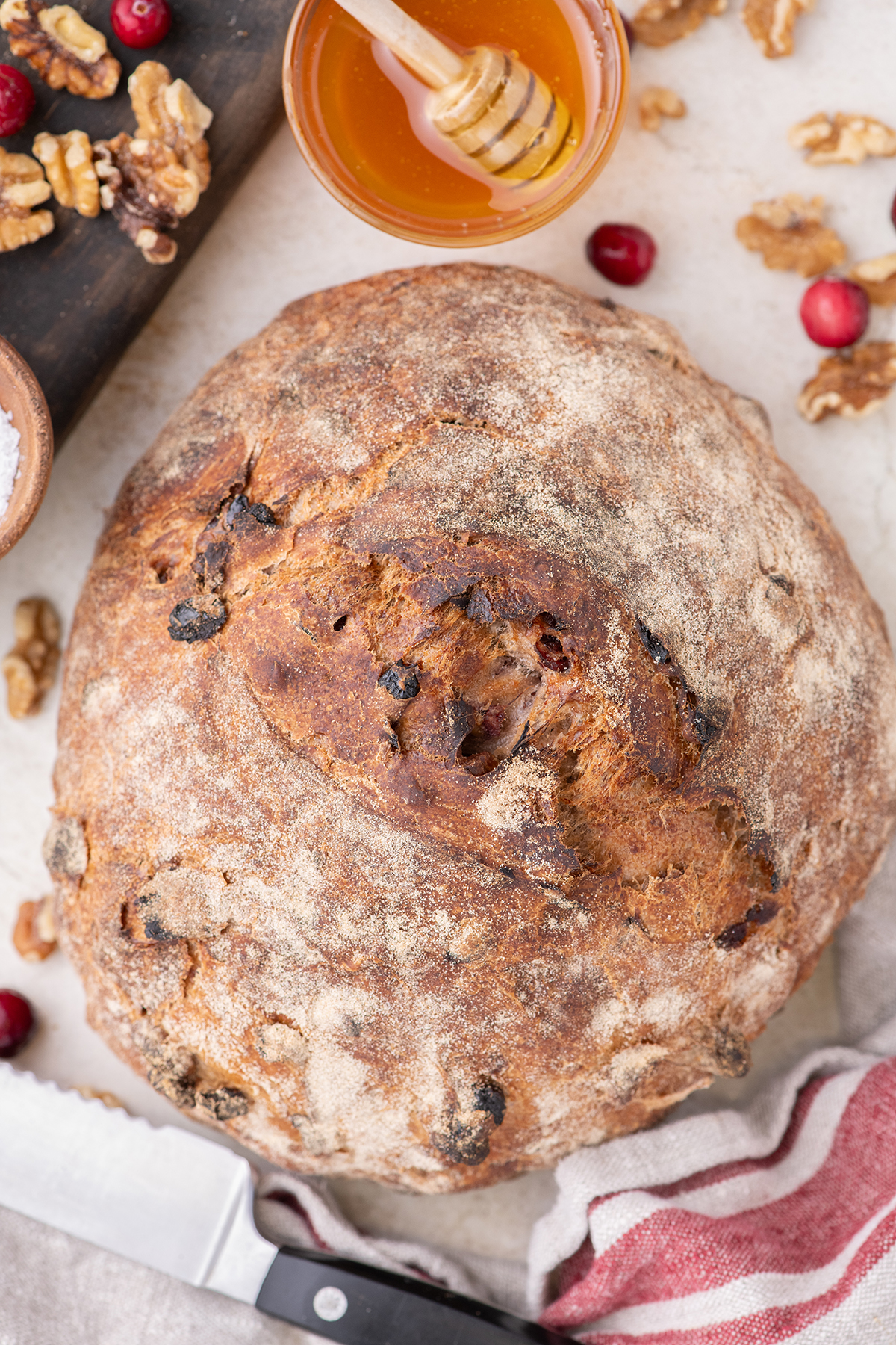 A round loaf of homemade bread surrounded with a kitchen towel with a red stripe.