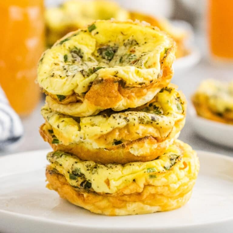 Egg muffins cooked in a muffin tin stacked on a white serving dish.