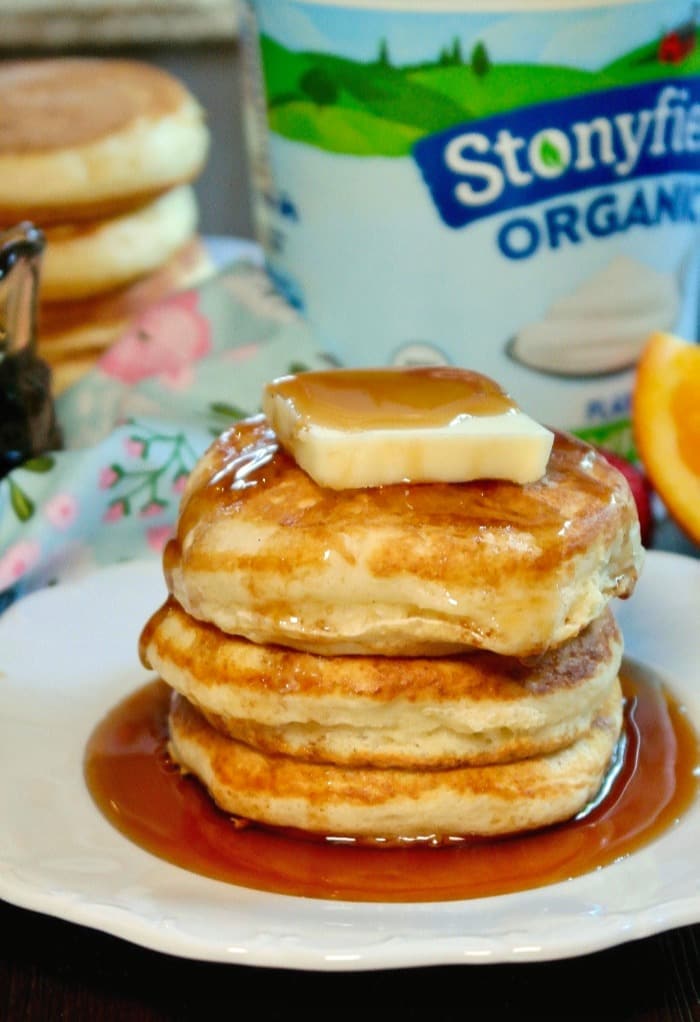 A stack of fluffy pancakes with butter and syrup