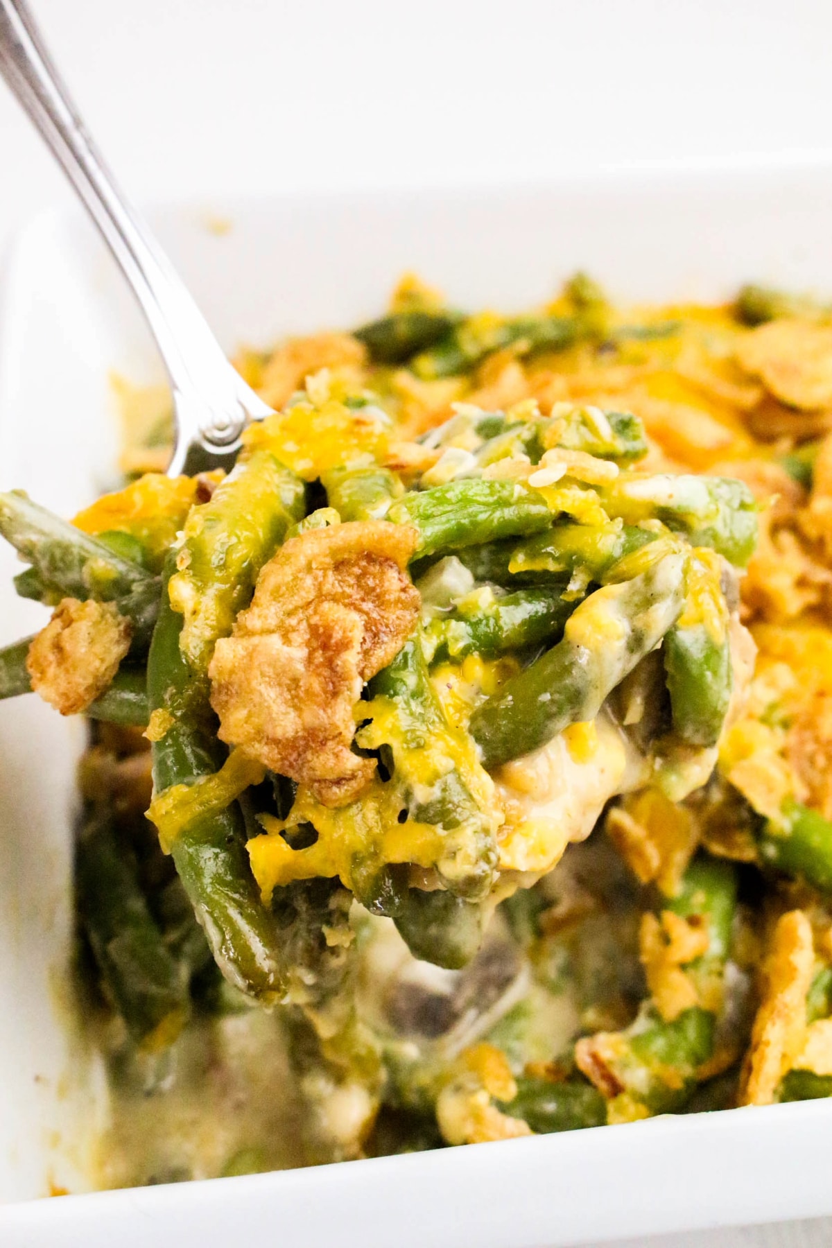 Green bean casserole with fresh green beans in a white dish.