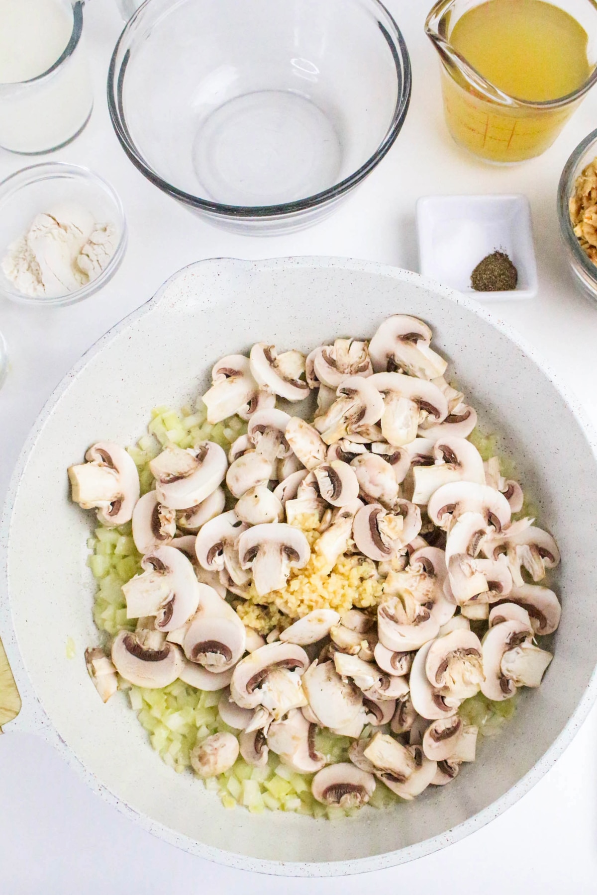 Sliced mushrooms with diced onion in a saute pan.