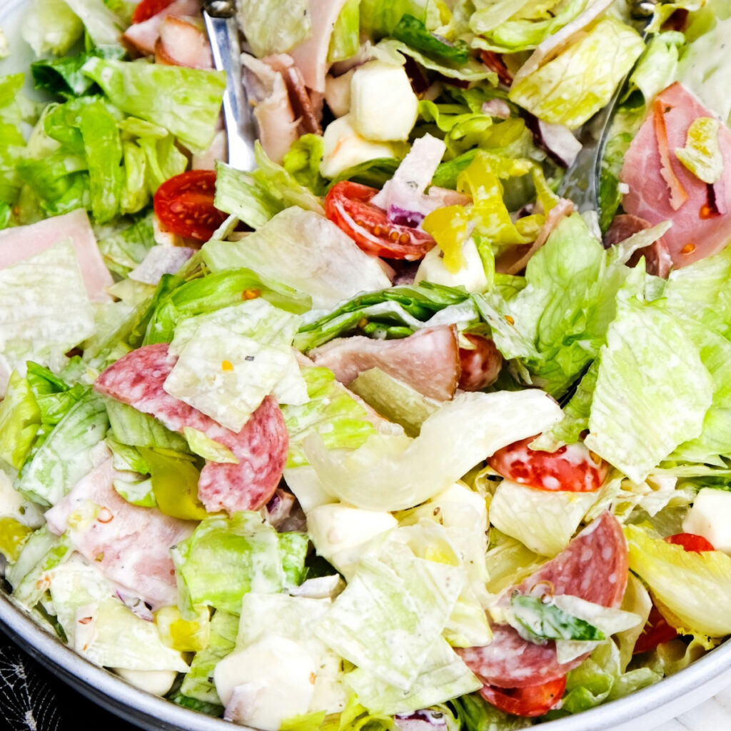 Italian grinder salad in a serving bowl with chopped lettuce and meats.