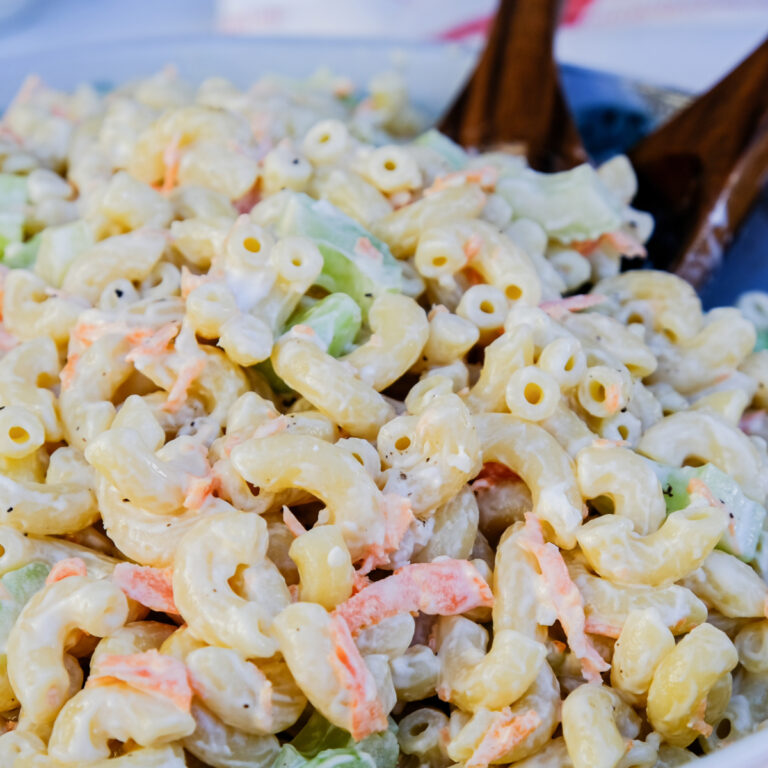 Hawaiian macaroni salad in a large bowl with wooden serving spoons.