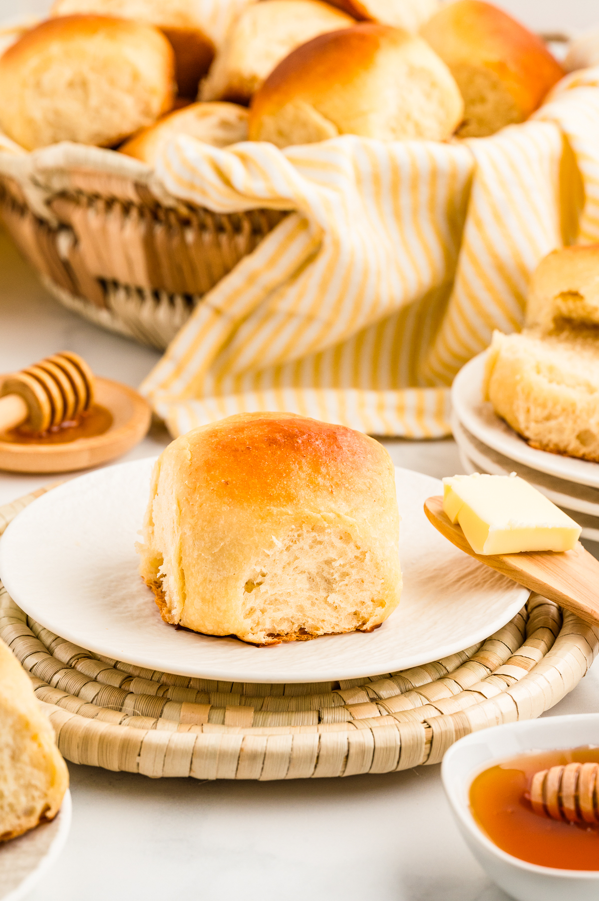 Dinner roll on a white plate with butter on the side.