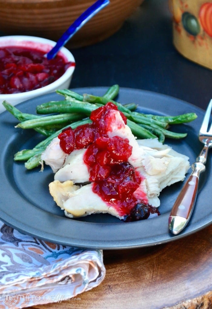 Healthy Cranberry Sauce without sugar topped on slices of turkey on a black plate with green beans #Healthy #CranberrySauce #LowCarb | www.thefoodieaffair.com