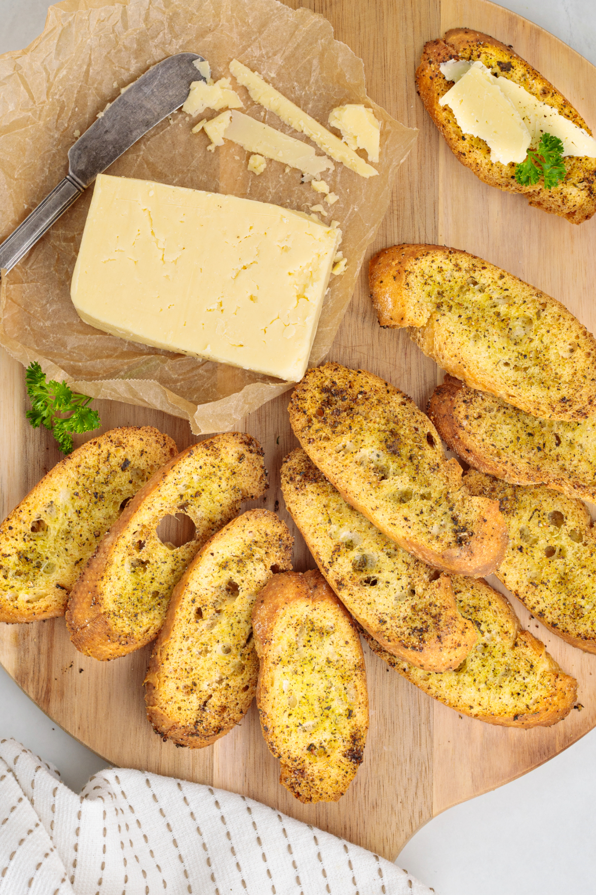 Homemade baguette crackers on a cutting board with a block of cheese on the side.