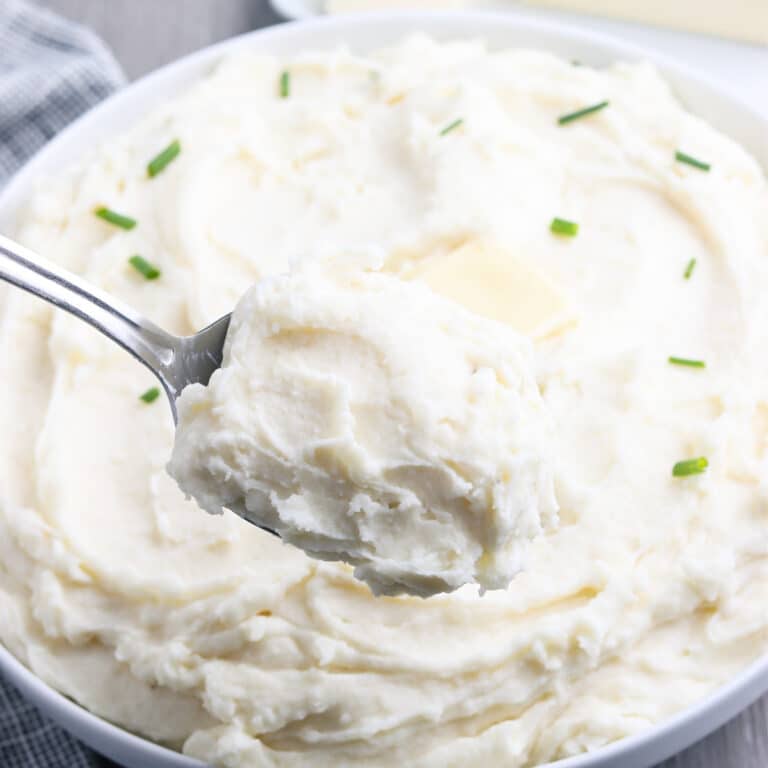 A spoonful of mashed potatoes in a white serving bowl.