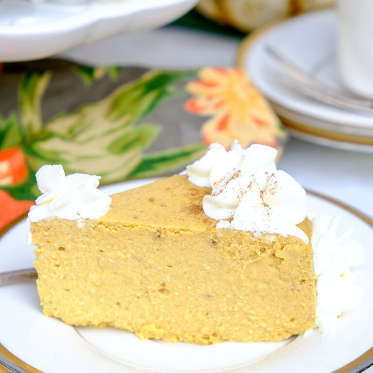 A slice of low Carb pumpkin cheesecake on a white plate with a gold rim ready to enjoy.