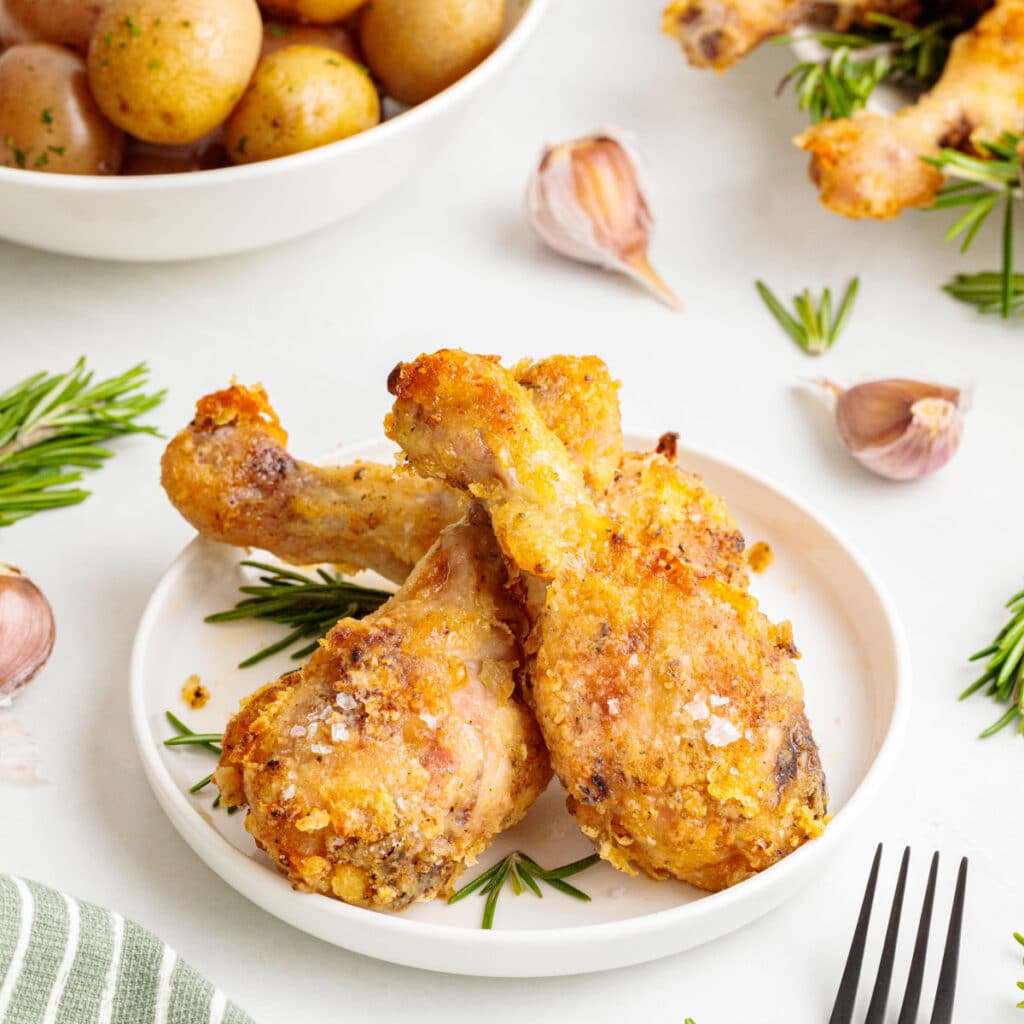 Baked chicken drumbsticks on a white serving plate.