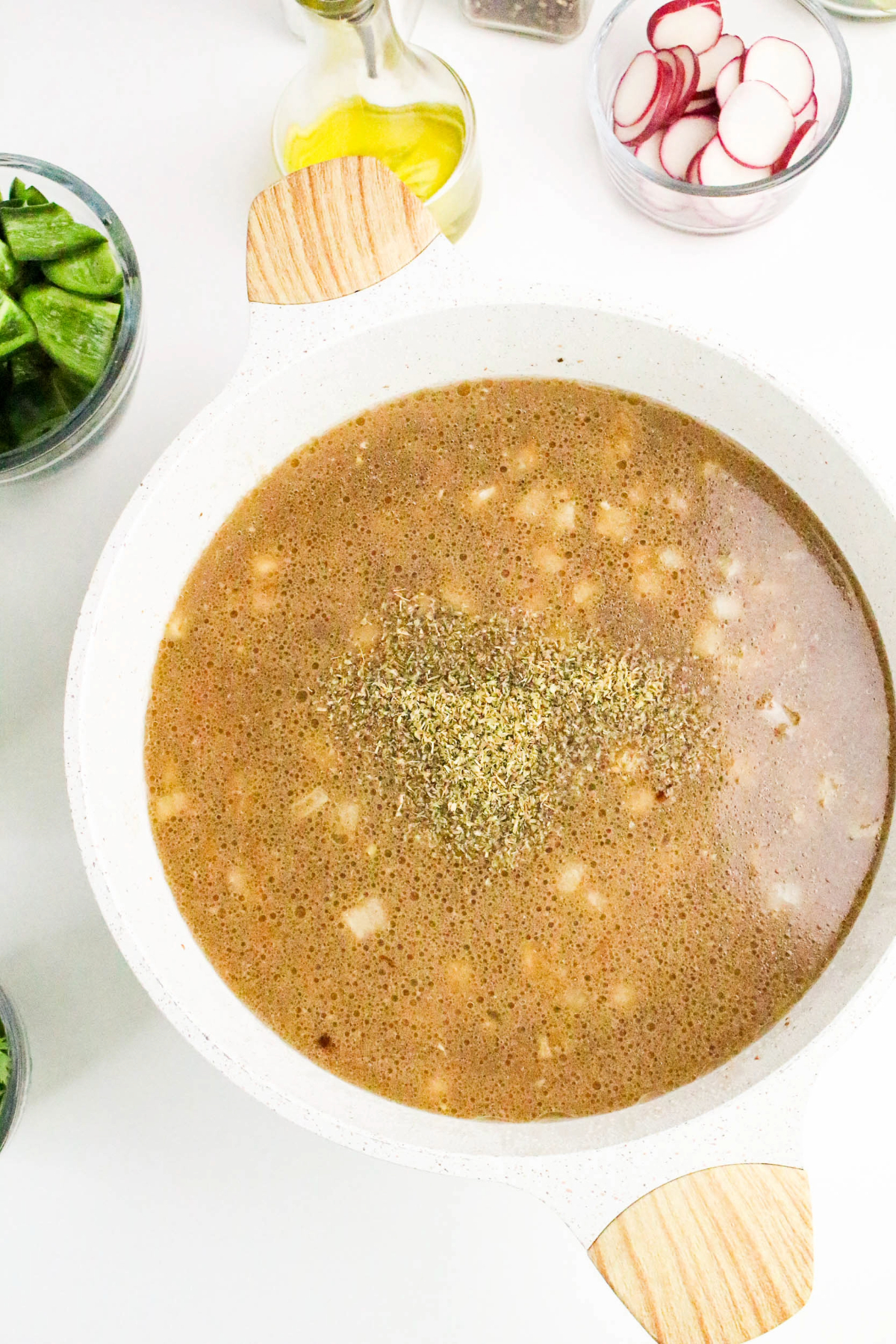 Broth added to diced pork in a white stock pot.