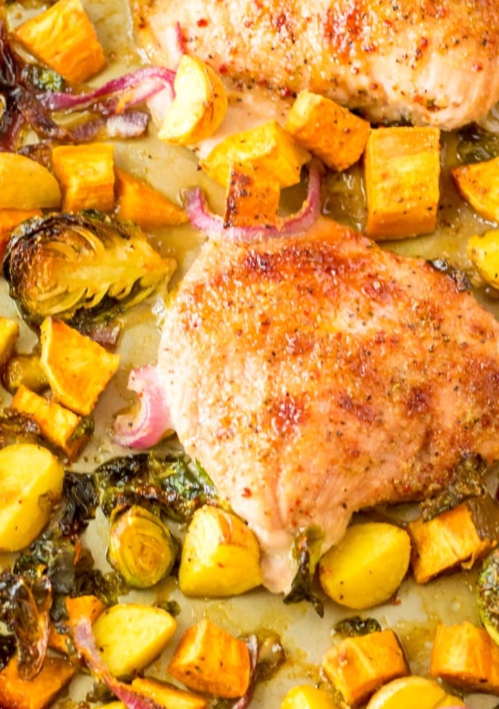Top vies of turkey breast cooked with vegetables on a sheet pan.