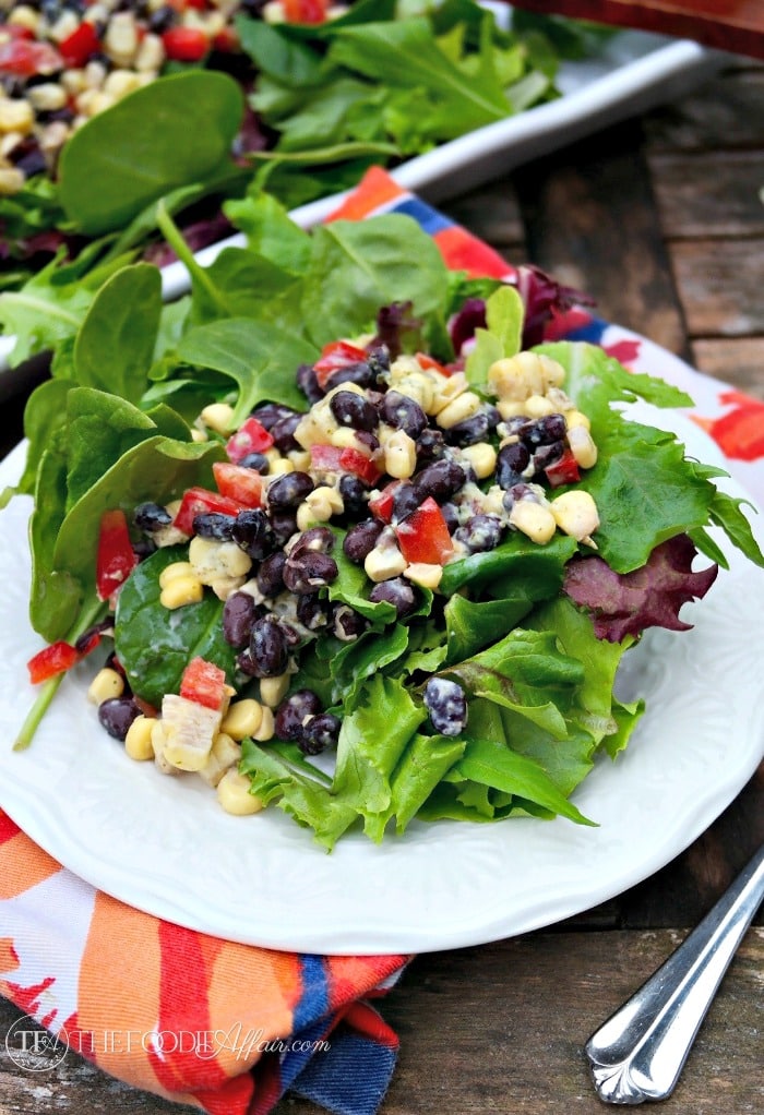 Black Bean and Corn Salad Recipe Over A Bed Of Greens on A White Plate