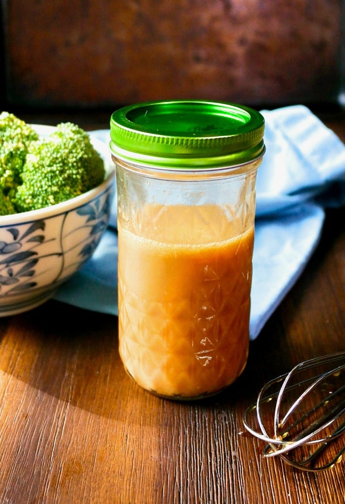 Homemade stir fry sauce in a mason jar with a whisk on the side