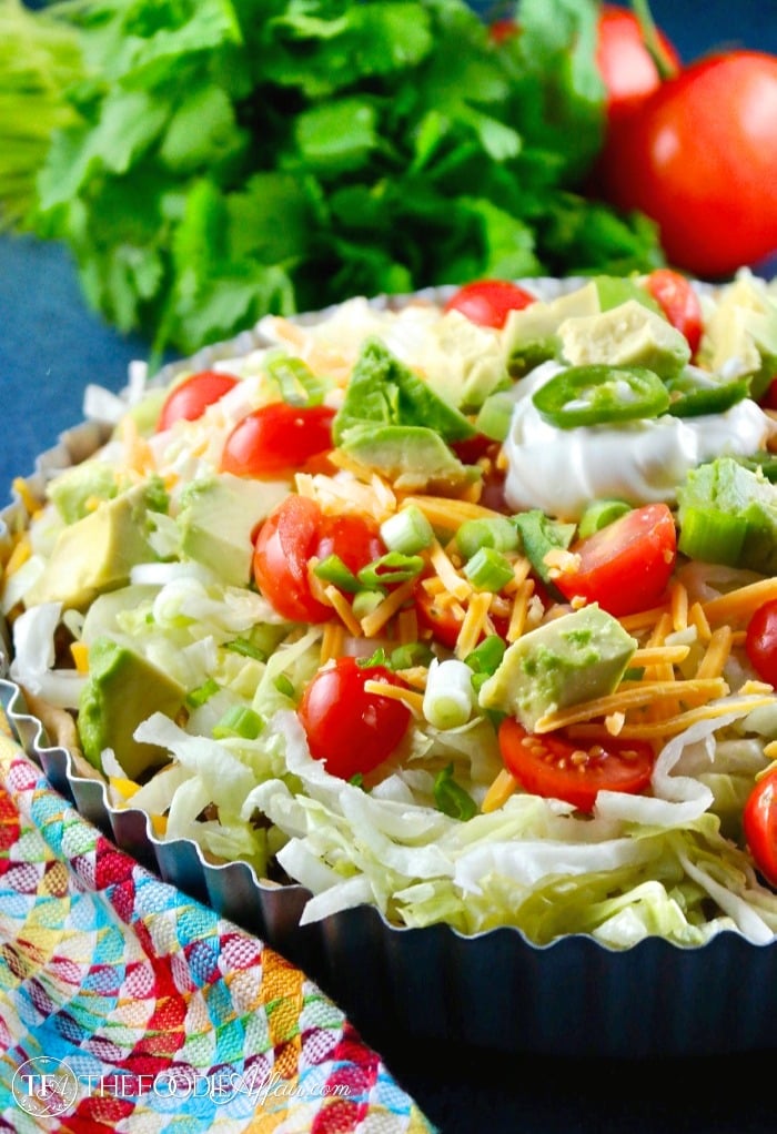 taco pie topped with lettuce and tomatoes