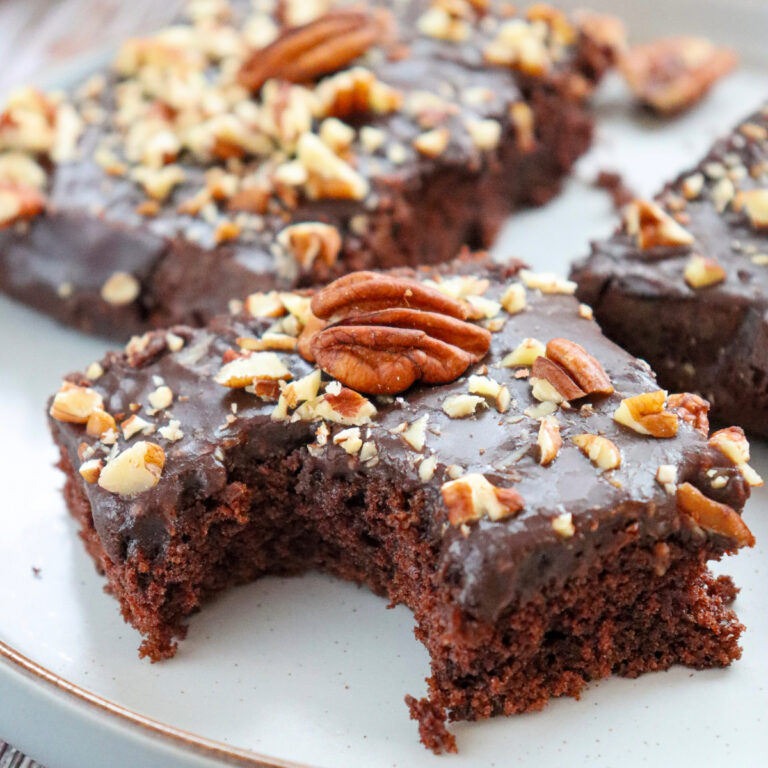 A slice of Texas sheet cake topped with chopped pecans.