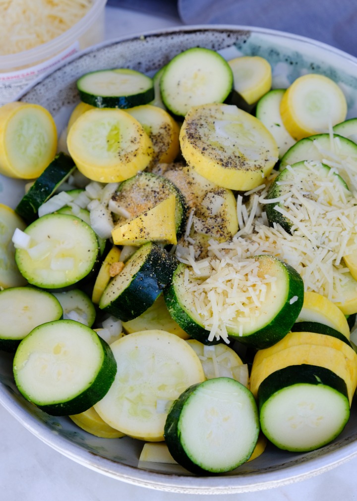 Sliced zucchini in a ceramic bowl with seasoning on top.