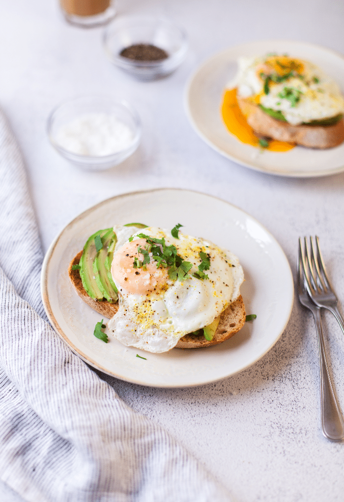 Breakfast plates with eggs and toast on white plates.