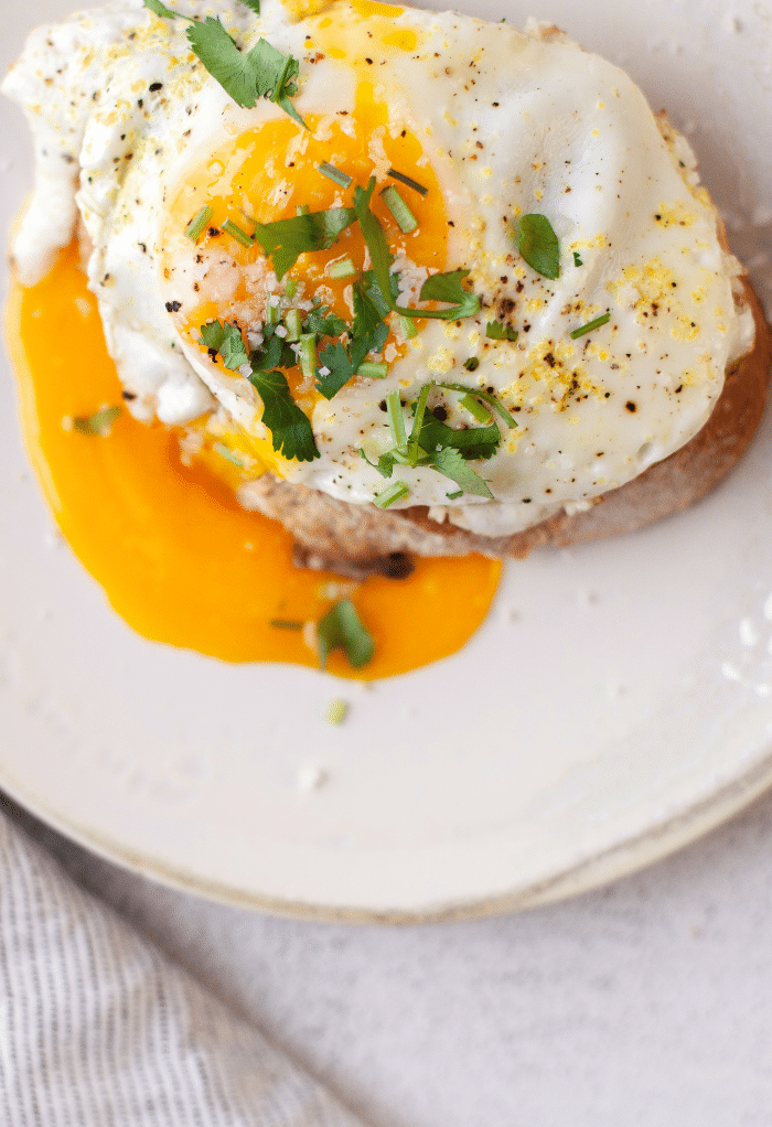 Top view of a egg over toast on a white plate.