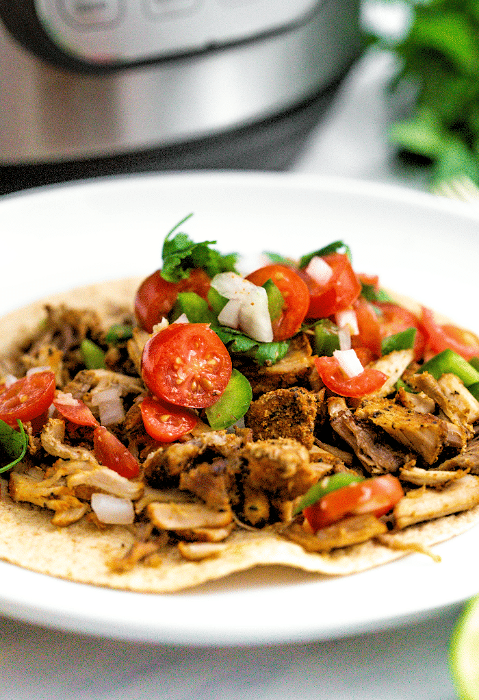 A close view of pork carnitas made in an instant pot on a white plate ready to eat.