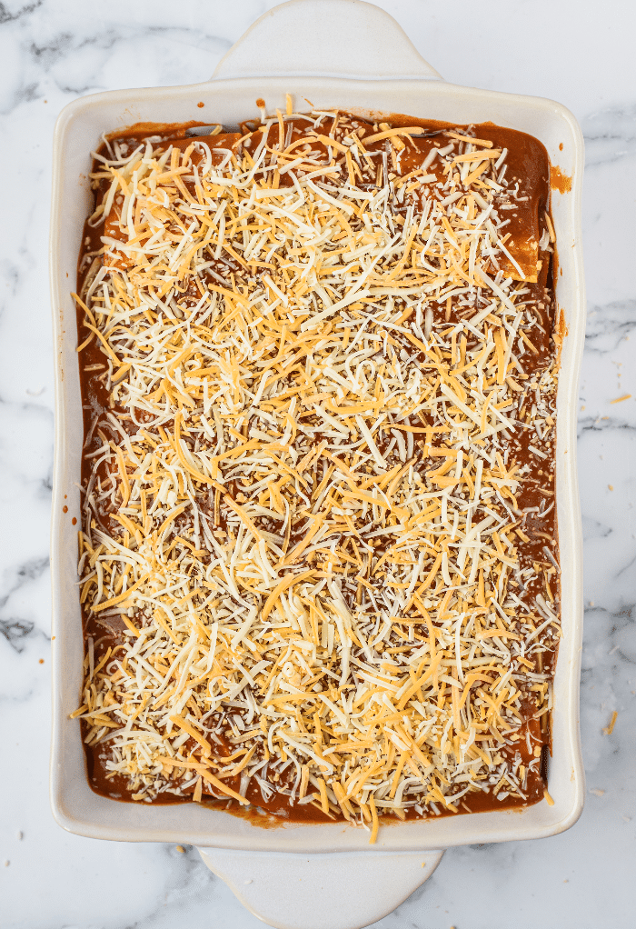 Cheese on top of enchilada sauce before baking.